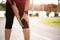 Young fitness woman runner feel pain on her knee in the park. Outdoor exercise activities concept