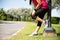 Young fitness woman runner feel pain on her knee in the park. Outdoor exercise activities concept