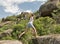 Young fitness woman running barefoot at mountain rocks