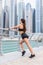 Young fitnesswoman runner stretching legs after run on skyscrapers background. Sport Concept