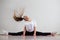 A young flexible fat woman sits in a transverse twine and waves her hair against a white background