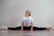 A young flexible fat woman sits in a transverse twine and waves her hair against a white background