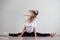 A young flexible fat woman sits in a transverse twine and waves her hair against a white background