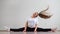 A young flexible fat woman sits in a transverse twine and waves her hair against a white background