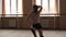 Young flexible female choreographer practicing contemporary dance elements at studio in slow motion