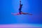 Young flexible girl isolated on blue studio background. Young female model practicing artistic gymnastics. Exercises for