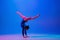 Young flexible girl isolated on blue studio background. Young female model practicing artistic gymnastics. Exercises for