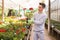 Young florist cultivating potted geranium