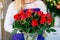 Young florist woman making beauty bouquet of red roses