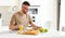 Young focused handsome man working remotely on laptop in modern kitchen at home