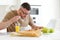 Young focused handsome man working remotely on laptop in modern kitchen at home