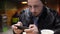 Young, focused man playing game on smartphone sitting in cafe