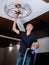 A young, focused man is replacing a lamp in a chandelier.