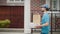A young food delivery man walks through a modern, pleasant neighborhood. A man in a cap and T-shirt delivers pizza and