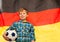 Young football fan with a ball against German flag
