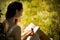 Young foxy haired woman reading book in nature.