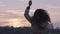 Young free happy woman dancing on background of urban landscape at sunset