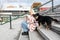 Young freelance expat woman sitting on the stairs of office building drinking coffee and working on laptop computer with her dog