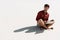 Young freelancer sitting on sandy beach with laptop