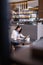 young freelancer writing in notebook near laptop in restaurant, blurred foreground.