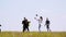 Young friends having fun playing with a ball in summer field on the background of flying swallows