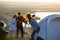 Young friends looking through telescope on the hill at summer evening - touristic travelers