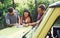 Young friends reading map that is on the hood of modern green jeep in the forest