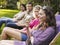 Young Friends In Row On Deckchairs At Garden