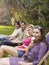 Young Friends In Row On Deckchairs At Garden