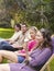 Young Friends In Row On Deckchairs At Garden