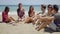 Young friends sitting on the beach chatting