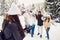 Young friends in winter coats having snowball fight in winter nature