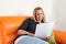 Young frown woman lying on couch reading a paper