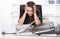 Young frustrated woman is sitting in front of a pile of files