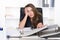 Young frustrated woman is sitting in front of a pile of files