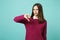 Young fun sad upset perplexed disturb brunette woman girl showing thumbs down posing isolated on blue wall background