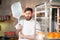 A young funny baker with a pizza spatula in his hands against the backdrop of an oven.