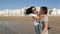 Young Funny Couple in Sunglasses Piggybacking on the Beach. Friends Together Having Fun. Sea is on Background.