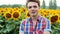 Young funny happy farmer looking at the camera and sings at sunset, sunflowers field