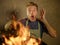 Young funny and messy home cook man with apron in shock holding pan in fire burning the food in kitchen disaster and domestic cook