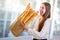 Young and funny woman eating baguettes in front of the bakery store