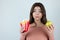 Young funny woman holding fried potatoes in one hand and apple in another standing with potatoe in mouth on isolated white