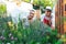 Young gardener in garden smelling flower, sunny nature