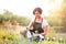 Young gardener in green apron sprinkling plants, garden