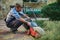 Young gardener landscaper placing the empty filter on the cordless electric lawn mower. Garden maintenance. Landscaping