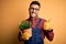 Young gardener man wearing working apron gardening plat for hobby over yellow background happy with big smile doing ok sign, thumb