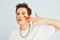 Young gay man is standing in the studio and posing for a camera. Painted by multi colored makeup