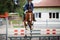 Young gelding horse and adult man rider jumping during equestrian showjumping competition in daytime