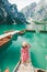 young gentle woman in red checkered dress barefoot walking by wooden stairs of boat station leads to lake