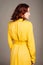 Young ginger woman in yellow shirt dress. Female bright trench at neutral studio background. Inner life